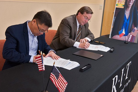 Two men at a table signing papers.