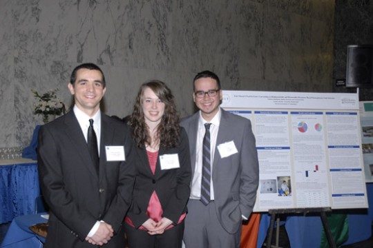 People posing next to display at event