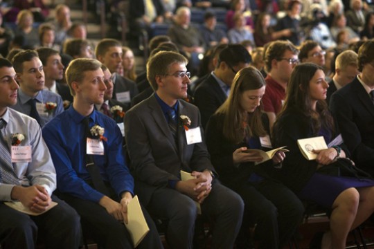 college students sitting in a row in a field house.