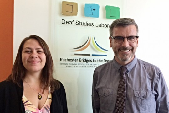 Two people posing in front of "Deaf Studies Laboratory" sign