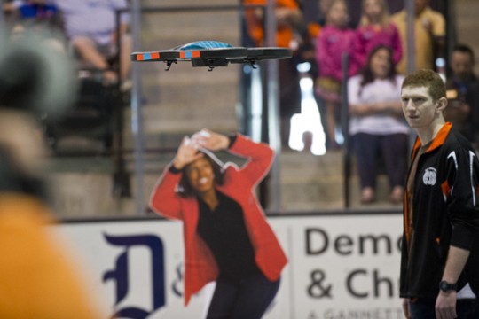 a cardboard cutout of a person ducking as a drone flies in an arena.