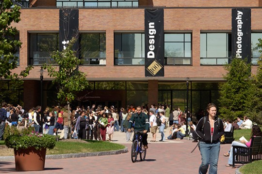 A group of people stands outside Gannett Hall on RIT's campus.