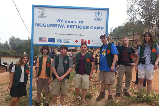 People gathered in front of "Welcome to Mugombwa Refugee Camp"