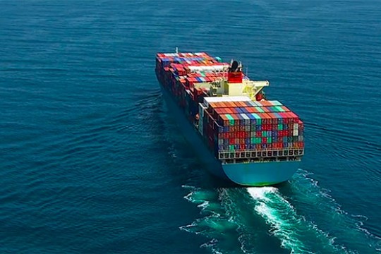 An aerial view of a large cargo ship sailing across open ocean.