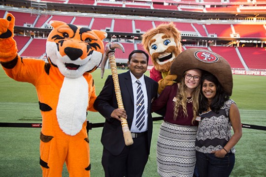 People posing in stadium with tiger mascot