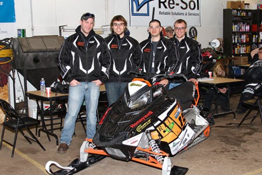 People posing by Snowmobile