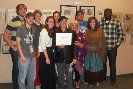 People gathered for picture in front of newspapers