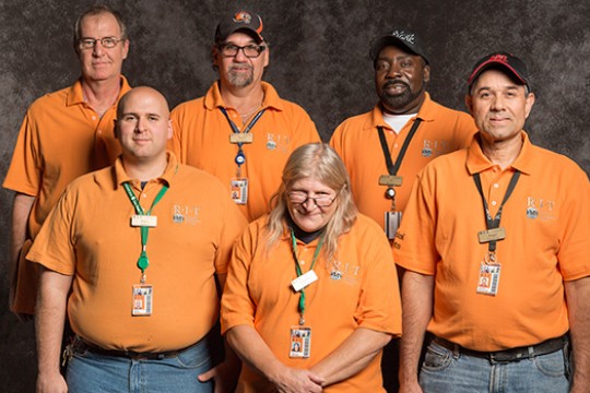 Team poses together in matching orange polos.