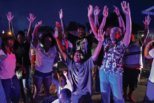 A group of people hold their arms up in the air. 