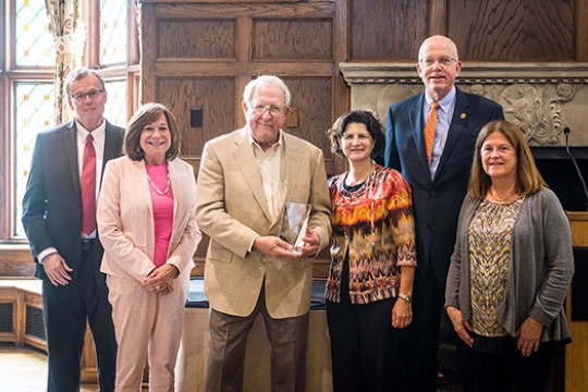Person holding award surrounded by faculty.