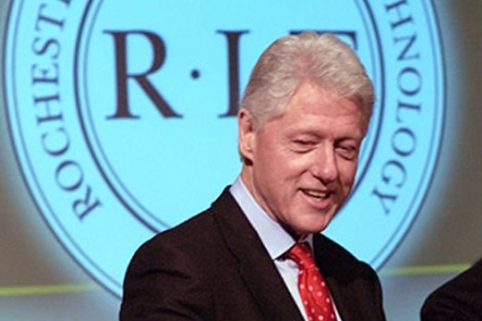 President Clinton in front of RIT logo
