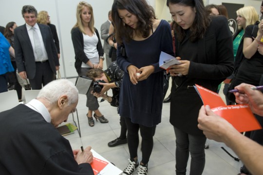 people surrounding person signing papers.