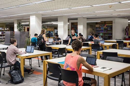students sitting at tables in the library.