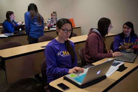 women at desks wearing matching purple women in computing shirts.