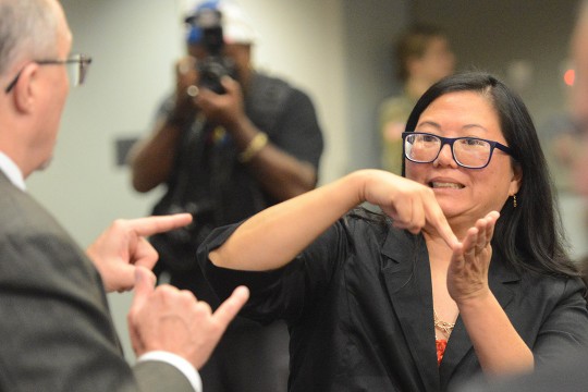 Tracy Tao-Moore communicates with another person using American Sign Language.