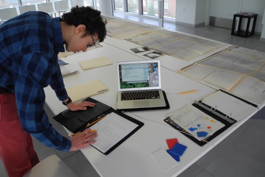 Anglemyer leaning over a desk in the Vignelli Center doing work