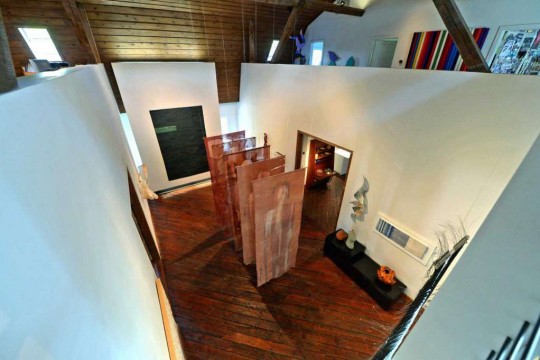 Four white walls within a larger room that display textile art pieces