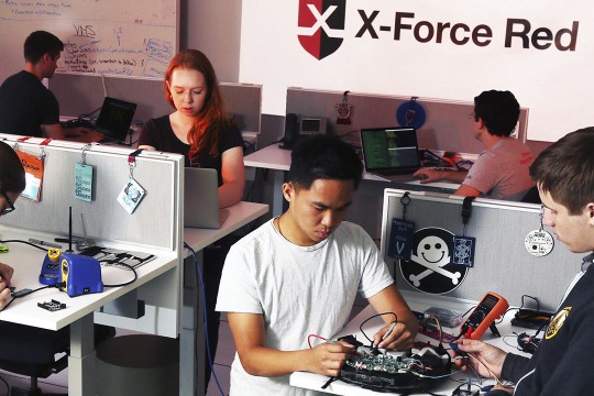 Students sit in cubicles testing electronics
