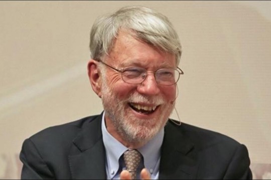 Head-and-shoulders view of man with glasses and beard laughing.