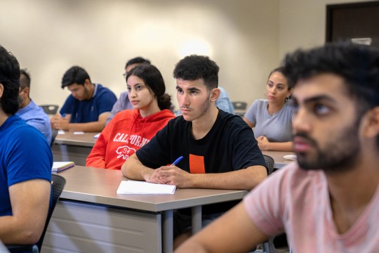 Students sit at desks in classroom.