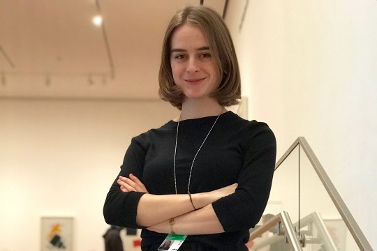 Student stands on stairwell at art museum.