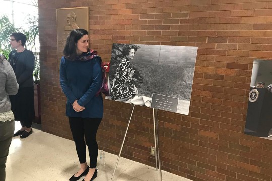 Woman stands next to black-and-white photo of Lady Bird Johnson.