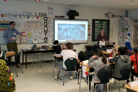 Man stands in front of class of elementary school children.