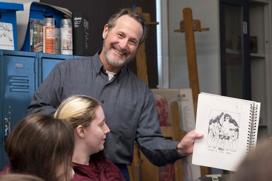 Man poses with cartoon drawing of chickens.