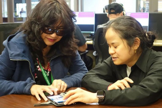 Two people look at smartphone.