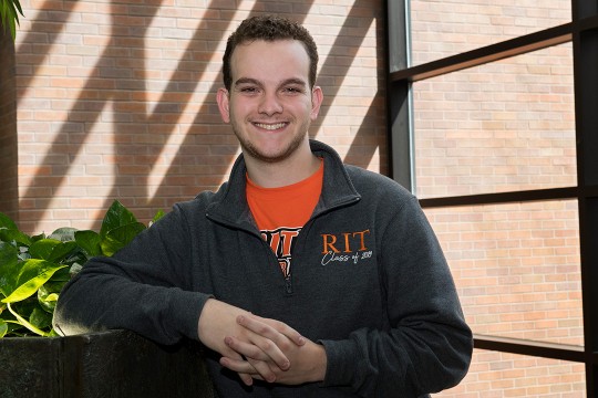 Student stands in front of window.