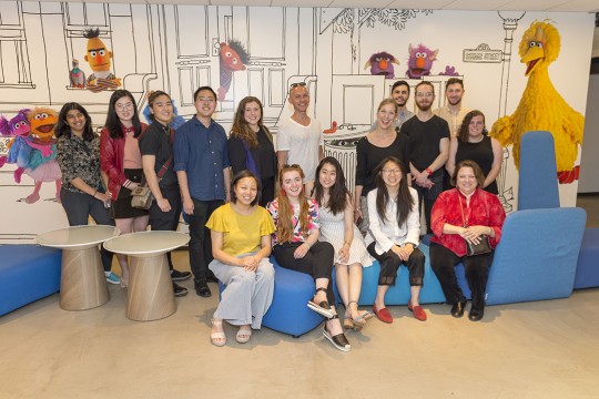 a group of people in front of a Sesame Street mural