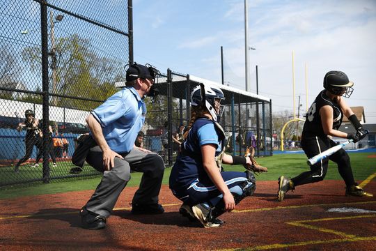 Umpire stands behind catcher during softball game.