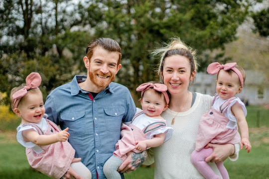 Parents hold triplet girls.