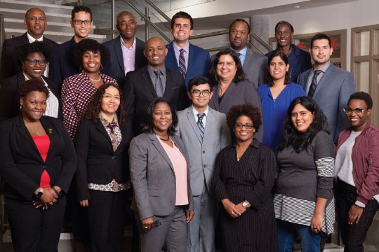 Group of people stands in three rows on stairwell.