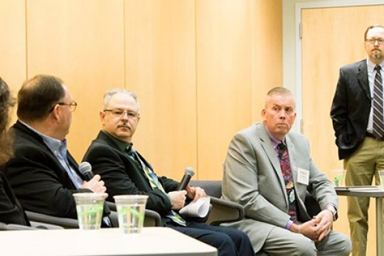 panel speakers in chairs next to a podium