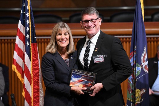 Man and woman pose holding award.