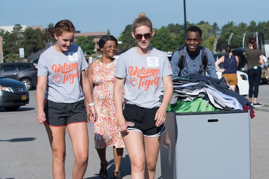 Students and parents bring items in cart for move-in day.