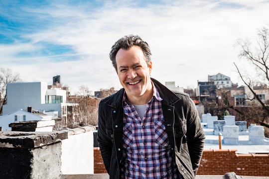 Man stands on roof of brick building.