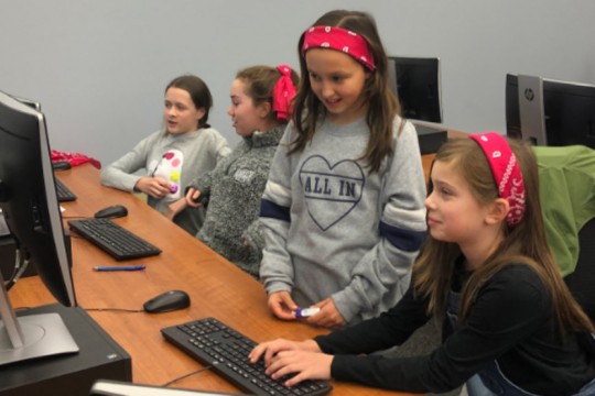 Girls at table with computers.