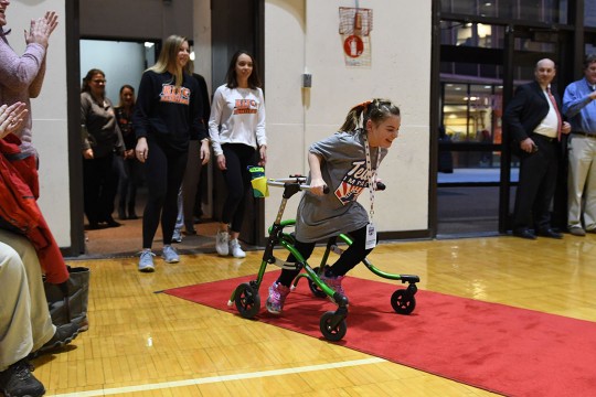 Girl using walker runs down red carpet in Clark Gym.