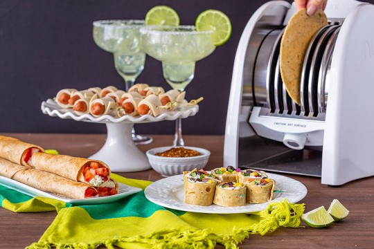 Table with tortilla toaster and platters of tortilla-based appetizers.