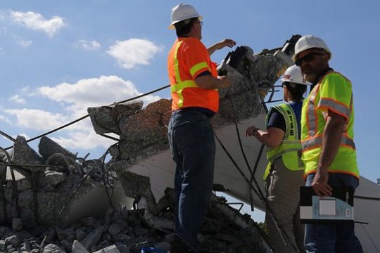 Workers survey collapsed bridge rubble.