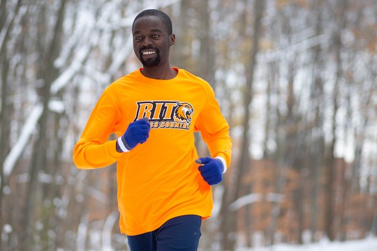 Man in orange long-sleeved shirt and blue gloves running.
