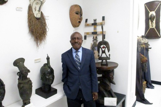 gallery owner standing in front of African art pieces.