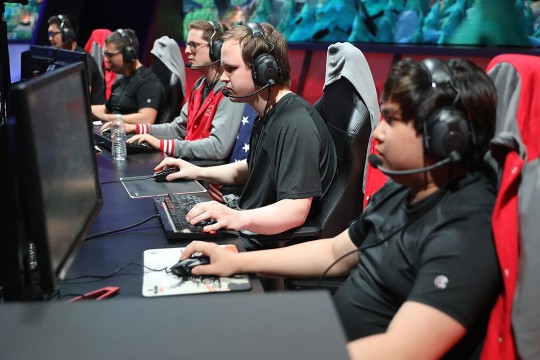 students wearing headset sitting a table with computers.