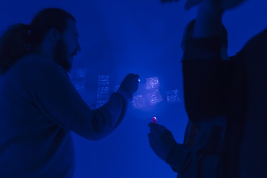 Students investigate the use of invisible ink with the lights turned off.