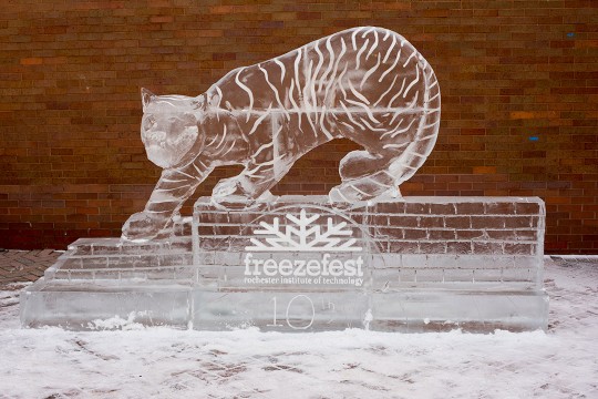 ice sculpture of tiger standing on brick wall.