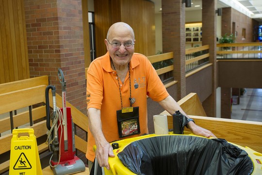 custodian standing with cleaning cart.