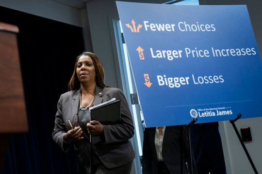 woman walking behind poster that reads: Fewer choices, larger price increases, bigger losses.