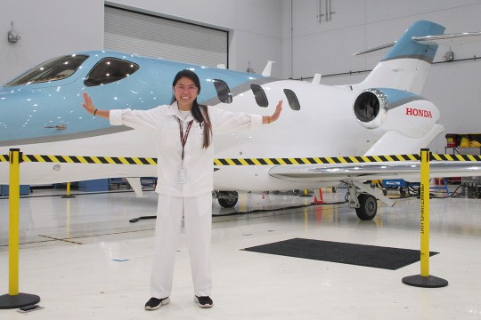 student posing in front of a new jet.